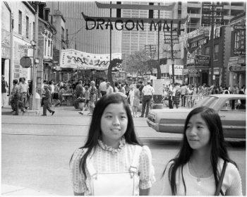 Image depicts two girls with street festival in backgound