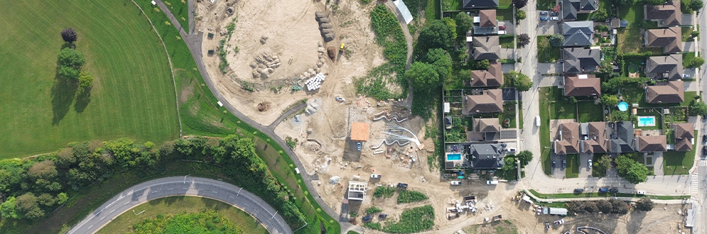 Aerial view of the park, showing an active construction site. The first phase of construction is complete, and the second phase is ongoing. The area surrounding the park features open grass fields, trees, roads and houses.