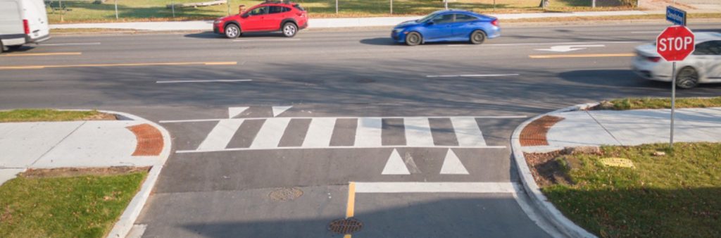 A raised crosswalk installed at a t-intersection of a local road and 4 lane major arterial road. The raised crossing decrease driving speeds, increase drivers’ compliance with posted signage and increase yielding to people crossing