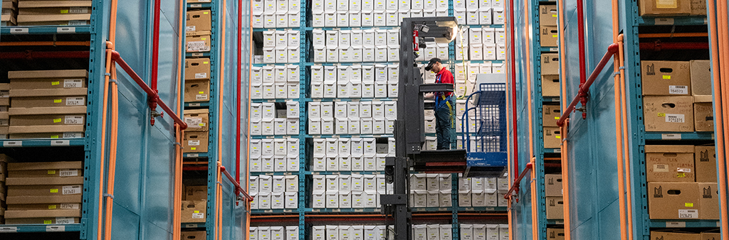 Worker stands on a lift elevated in the stacks of the archives
