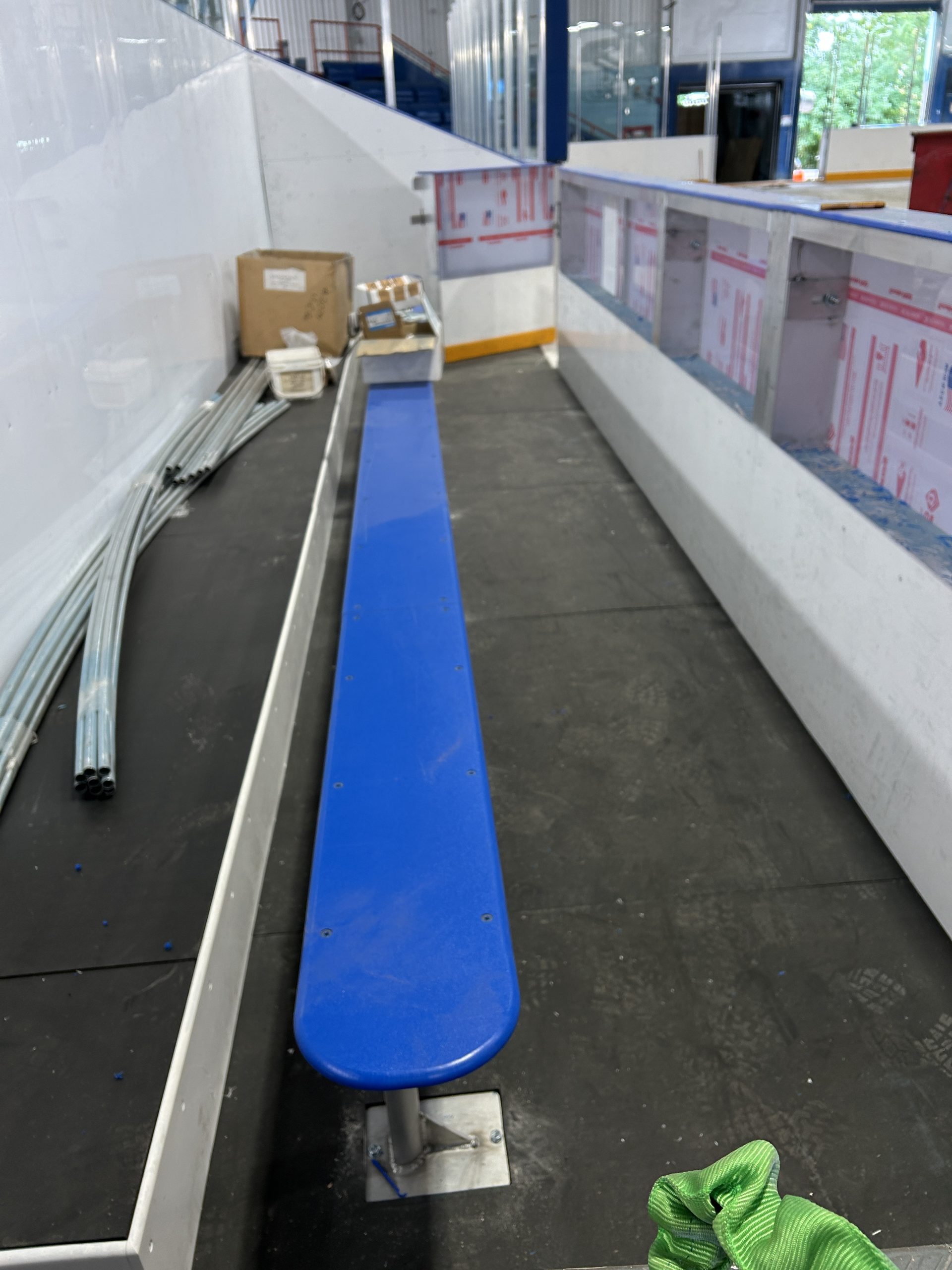 A blue player bench installed for an indoor rink, next to dasher boards.