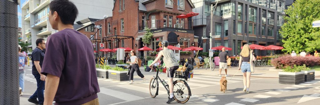 People walk and cycle through an intersection that has restricted access for vehicles.