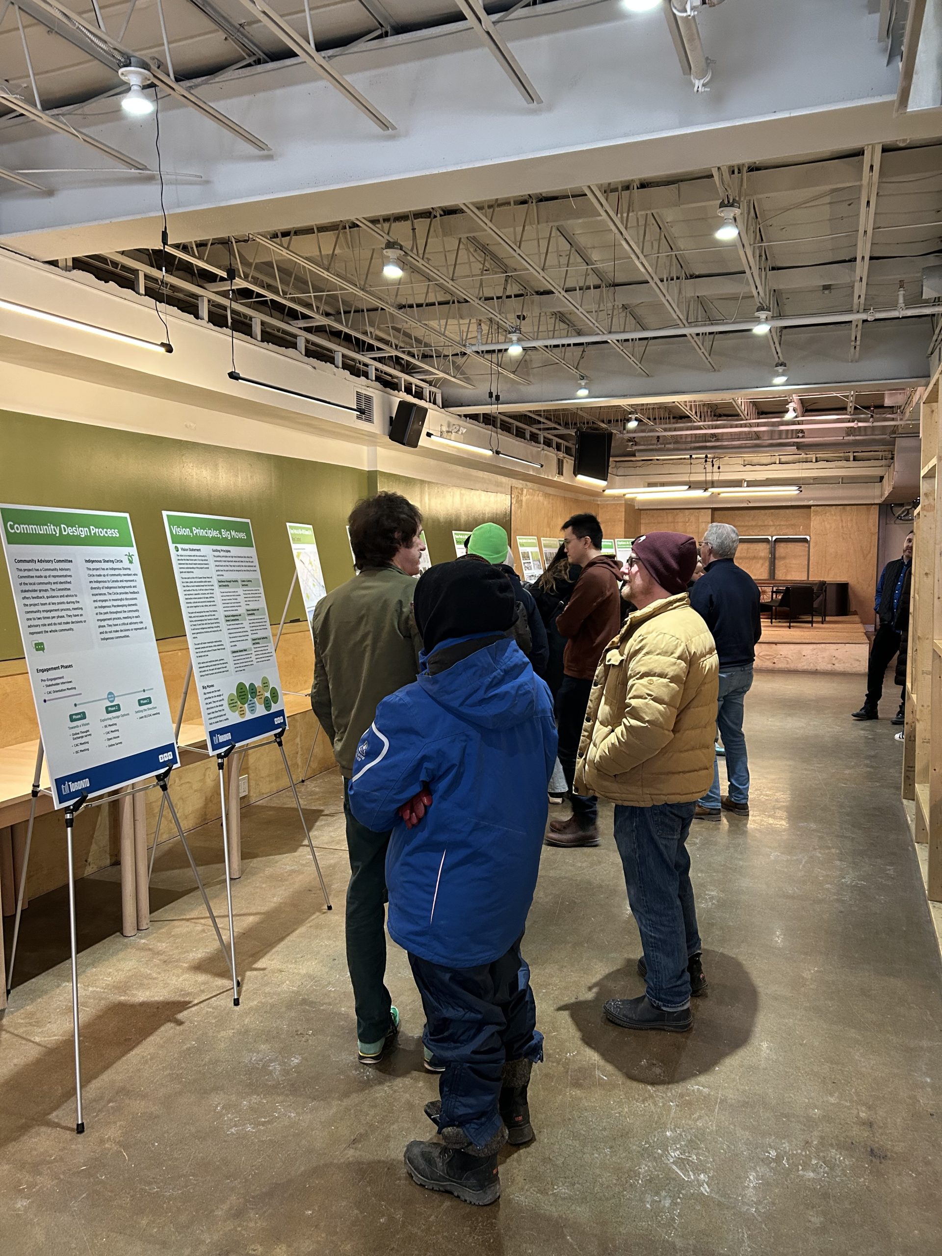 Photograph of community members reading the open house boards and talking to one another.