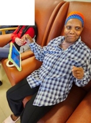 A resident sits on a couch and moves to the music playing from an iPad.