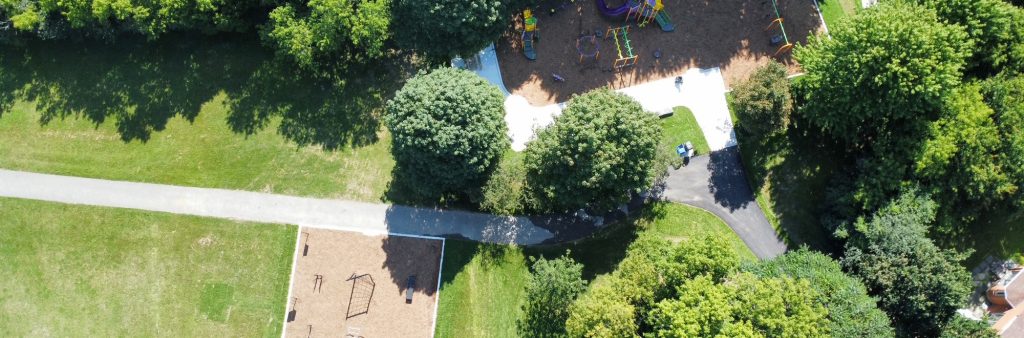 Aerial image of the new playground area and fitness area, with north towards the left. The fitness area is shown to the left of the image along the main walkway in the open lawn. The playground is to the right of the image off the main walkway and nestled among mature trees.