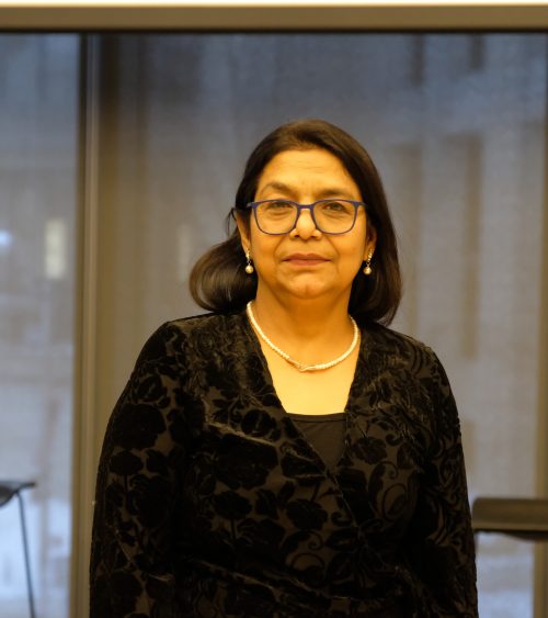 Headshot photograph of woman wearing black blazer, with glasses
