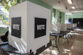 White privacy screens arranged on tables inside a polling location.