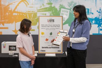 Kids Vote Weekend participant learning about the Tree of the Year voting activity at a voting place.