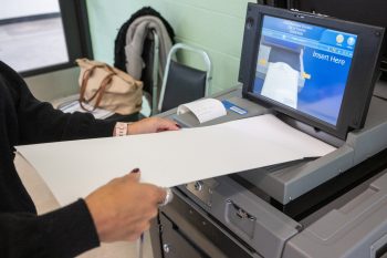 Person inserting a ballot into a vote-counting machine.