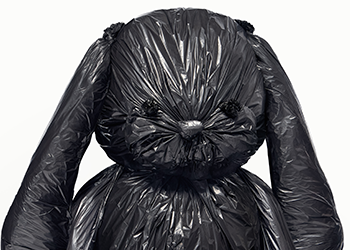 A stuffed bunny wrapped in a black garbage bag.